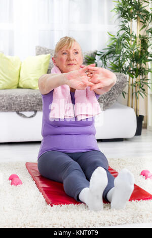 Senior donna facendo esercizi di stretching Foto Stock