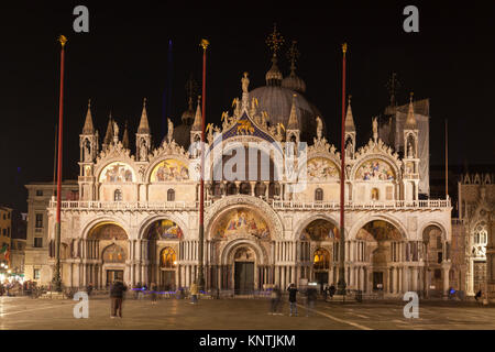 Facciata della Basilica di San Marco illuminata di notte, Piazza San Marco, Venezia, Veneto, Italia in una vista ravvicinata con pochi turisti in forgrou Foto Stock