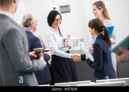 Coppia imprenditrice stringono le mani con il giovane collega di sesso femminile in aula magna Foto Stock
