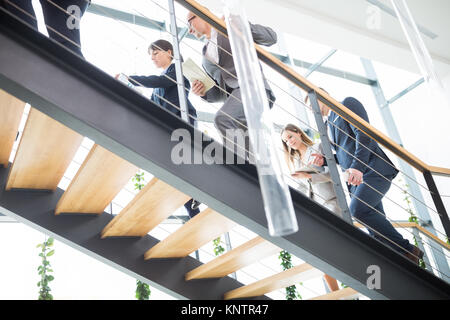 Basso angolo di visione dei colleghi di lavoro salendo le scale in ufficio moderno Foto Stock