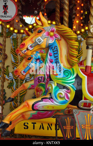 Vivacemente colorato dipinto fiera carosello cavalli su golden poli con le luci fairy su una corsa sulla riva sud del fiume Tamigi per celebrare. Foto Stock