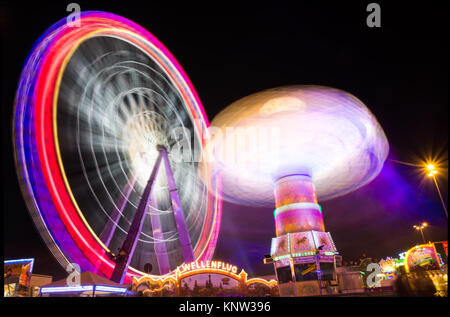 Ruota panoramica Ferris altalene di filatura lunga esposizione Festival montagne russe giostre Foto Stock