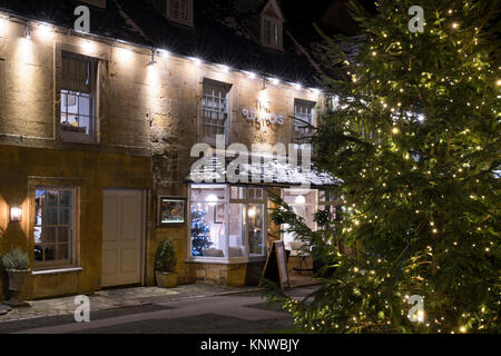 Albero di natale e decorazioni a notte nella parte anteriore delle vecchie scorte inn. Stow on the Wold, Cotswolds, Gloucestershire, Inghilterra Foto Stock