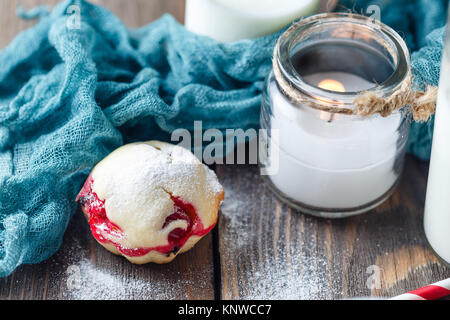 Muffin con mirtilli e cioccolato e una candela bianca in un candelabro di vetro su di un tavolo di legno di close-up Foto Stock