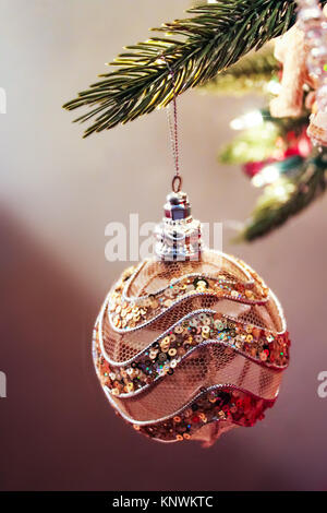 Glitter e maglia Natale oro e rosa ornamento appesa da albero con altri ornamenti sfocato dietro Foto Stock