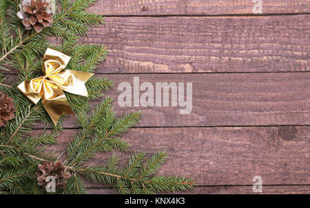 Albero di Natale decorato arco rosso, rami e coni su sfondo di legno Foto Stock