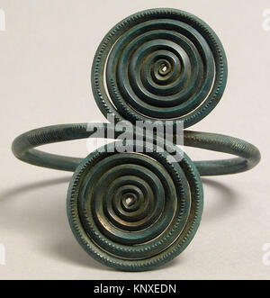 Una fascia da braccio dell'età del bronzo con design a spirale, realizzata in lega di rame, risalente al XIV-XII secolo a.C., che riflette la lavorazione dei metalli preistorici europei. Foto Stock