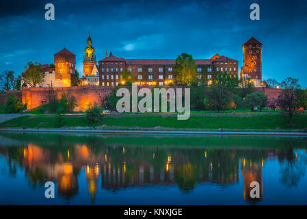 La Polonia città colore, vista di notte attraverso il fiume Vistola verso il castello illuminato fortificazioni sul colle di Wawel Cracovia in Polonia. Foto Stock