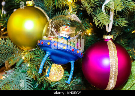 Spaceman dando segno di pace in blu alien razzo il tradizionale albero di Natale con il rosso e ornamenti di magenta Foto Stock