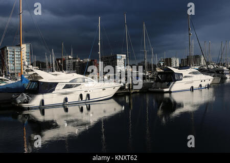 Porto turistico sul lungomare di Ipswich e edifici circostanti con nuvole tempeste molto scure e luce solare che illuminano le barche e gli edifici Foto Stock