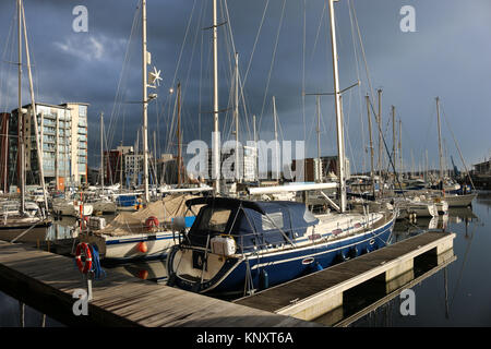 Porto turistico sul lungomare di Ipswich e edifici circostanti con nuvole tempeste molto scure e luce solare che illuminano le barche e gli edifici Foto Stock