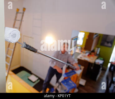 Un decoratore di verniciatura di un interno di una casa, di difficile accesso che coinvolgono i ponteggi Foto Stock