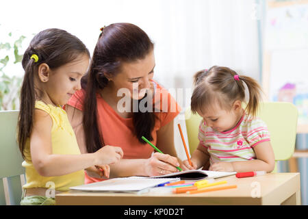 Insegnante mamma lavora con piccoli creativi Foto Stock