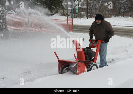 L'uomo operando un spalaneve a rimuovere la neve dal suo passo carraio a seguito di una tempesta di neve in speculatore, NY New York STATI UNITI D'AMERICA Foto Stock