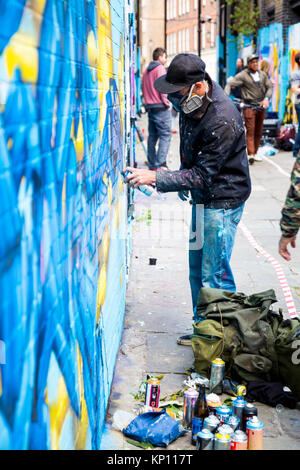 Graffiti artista di strada che indossa una maschera con respiratore spruzzare le pareti in Fleur Street, Londra, Regno Unito Foto Stock