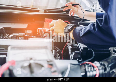 Auto meccanico con un multimetro voltmetro auto controllo di tensione della  batteria in corrispondenza di officina Foto stock - Alamy