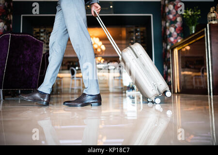 Imprenditore entrando in hotel con i bagagli. Foto Stock