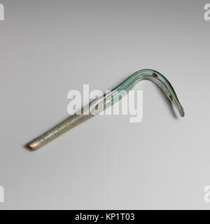 Questo strigil di vetro romano, risalente al III-IV secolo d.C., è realizzato in vetro blu-verde traslucido. È dotato di un lungo manico cilindrico cavo che si espande leggermente verso il basso, con una sezione della lama curva che ha un margine profondo che corre lungo, terminando con una punta arrotondata. La parte superiore dell'impugnatura è rotta e il pezzo mostra segni di agenti atmosferici. Foto Stock