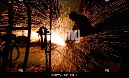 Operaio industriale con workin strumento tra le scintille. Foto Stock