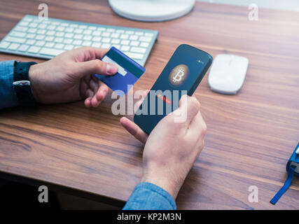 Mani tenendo la carta di credito e telefono. bitcoin acquisto online Foto Stock