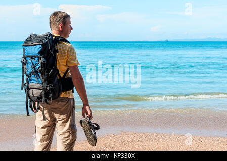 Turistico con uno zaino trascorre la vacanza sulla spiaggia, si ammira una splendida vista Foto Stock