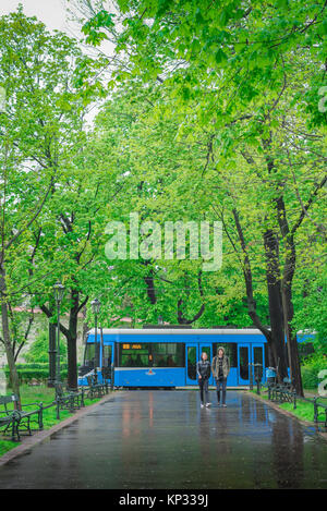 Giovane passeggiate pioggia, sotto una tarda primavera doccia di pioggia una coppia giovane a piedi attraverso il Parco Planty a Cracovia, Polonia. Foto Stock