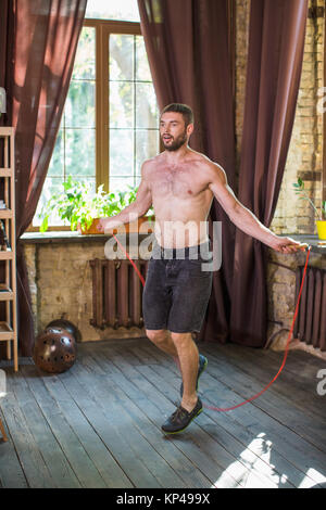 L'uomo facendo allenamento, il salto con la corda in salotto. Foto Stock