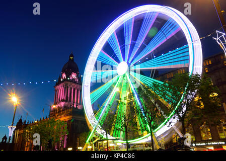 Il traffico che passa luna park e le luci di Natale da leeds town hall al crepuscolo Yorkshire Regno Unito Foto Stock