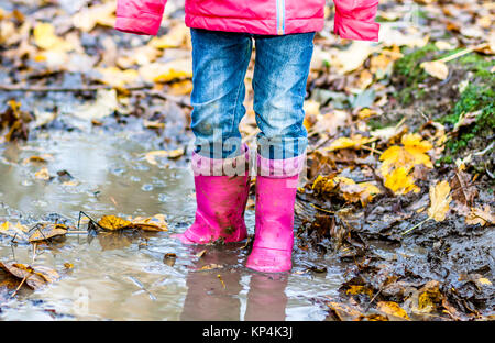 Bambina con rosa wellys nella pozzanghera sulla foresta Foto Stock