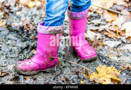 Bambina con rosa wellys nella pozzanghera sulla foresta Foto Stock