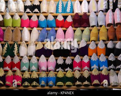 Chiusura del file di babouches scarpe in diversi colori sul display in una fase di stallo nel souk di Fez, Marocco Foto Stock