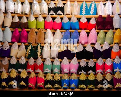 Chiusura del file di babouches scarpe in diversi colori sul display in una fase di stallo nel souk di Fez, Marocco Foto Stock