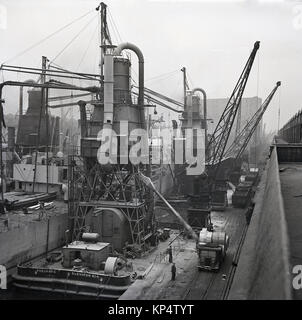 Degli anni Cinquanta, foto storiche che mostra i lavoratori e attività con navi e galleggianti pneumatici ascensori nel dock 9, il King George V Dock ( KGV) ultimi del dock per essere costruito e una dock che era in grado di acomodate grandi navi, porto di Londra, Inghilterra, Regno Unito. Foto Stock