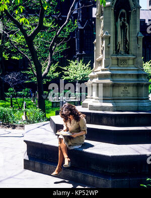 Maggio 1982,New York,donna leggendo un libro,Astor croce,chiesa della Trinità cimitero,il quartiere finanziario,Lower Manhattan,New York City, NY,NYC,USA, Foto Stock