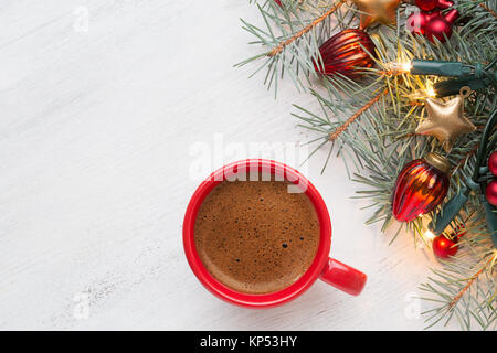 Tazza di caffè e il ramo di abete con decorazioni natalizie e incandescente garland sul vecchio di legno malandata sfondo con spazio vuoto per il testo. Foto Stock