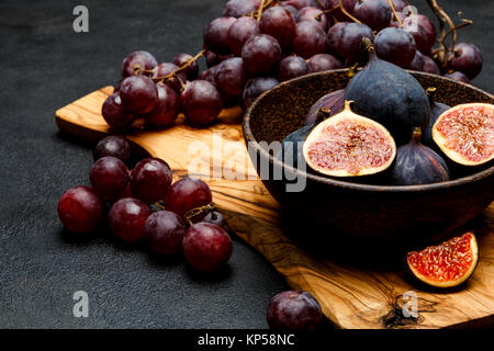 Uve mature e fichi sul scuro dello sfondo in calcestruzzo Foto Stock