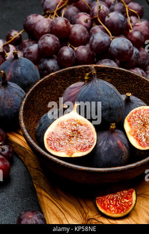 Uve mature e fichi sul scuro dello sfondo in calcestruzzo Foto Stock