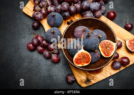 Uve mature e fichi sul scuro dello sfondo in calcestruzzo Foto Stock