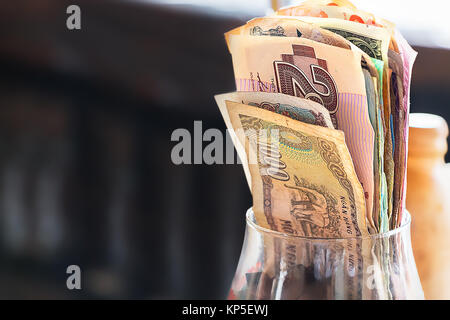 Un bicchiere con banconote closeup, in interni. Foto Stock