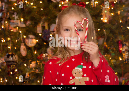 Scuola adorabili età ragazza tenendo premuto fino candy canne in forma di cuore per la stagione di festa di Natale Foto Stock