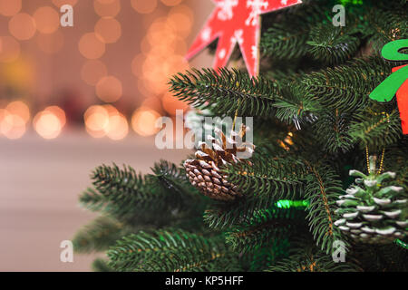 Fatte a mano in legno dipinto, stelle e fiocchi di neve e pigne su verde albero di Natale Foto Stock