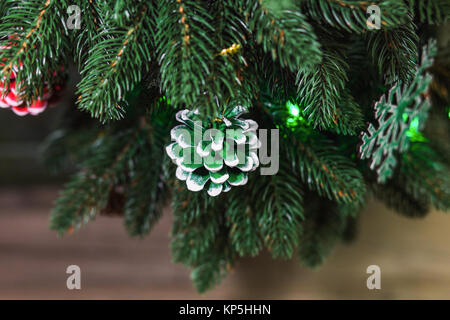 Close up dipinte a mano pigne decorazione su verde rami di albero di Natale Foto Stock