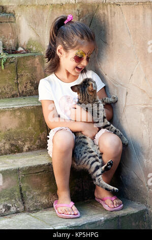 Bambina abbracciando tabby cat Foto Stock