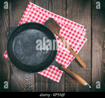 Vuoto nero tondo padella con un manico in legno su uno sfondo marrone, vista dall'alto, tonificazione vintage Foto Stock