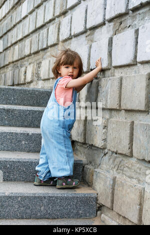 Baby girl in blu clother va giù per le scale Foto Stock