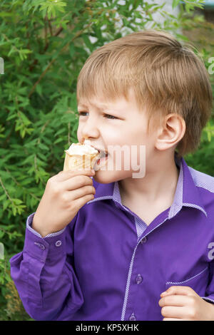 Foto verticale del ragazzo biondo sono mangiare gelato in estate Foto Stock