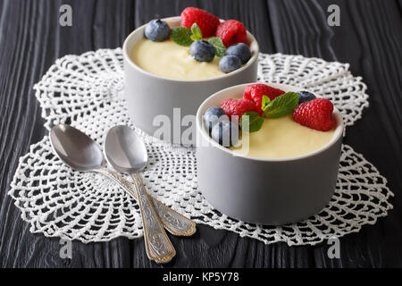 Budino alla vaniglia con frutti di bosco freschi e menta closeup sul tavolo orizzontale. Foto Stock