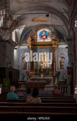 Corsica: la gente sui banchi della Eglise de l'Annunciazione, Annunciazione Chiesa, il più antico edificio della città (1450) nella Cittadella di Corte Foto Stock