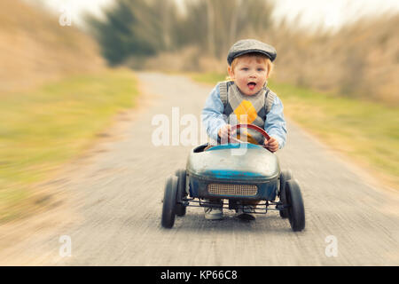 Ridendo ragazzo con la vettura del pedale Foto Stock