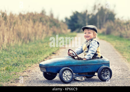 Ridendo ragazzo con la vettura del pedale Foto Stock